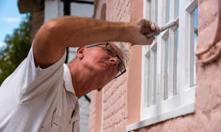 man paints house with white paint