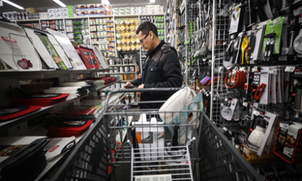 man with a shopping cart looks for products at a Bed Bath & Beyond store